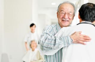 senior male patient and doctor hugging