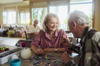 Two seniors in a center speaking with one another over puzzles