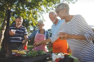 A group of seniors barbecuing together on a sunny day 