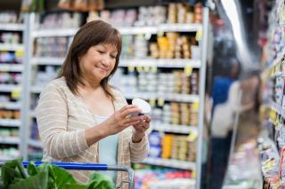 A woman reads the nutrition label on a product while shopping. 