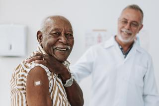 Senior smiling with doctor after getting flu shot